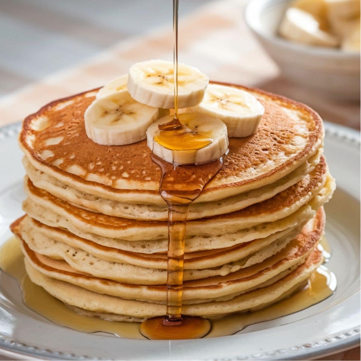 Stack of fluffy Banana Oat Pancakes topped with fresh banana slices and drizzled with golden maple syrup, perfect for a healthy and delicious breakfast.