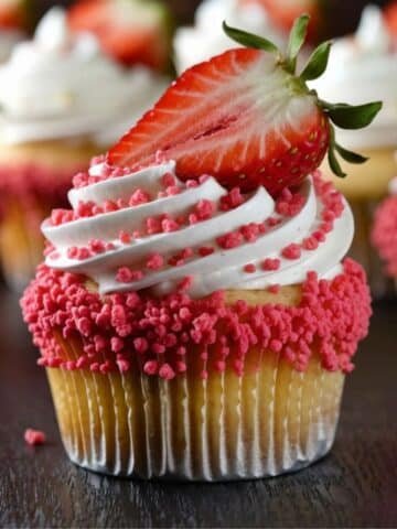 Decadent Strawberry Crunch Cupcakes topped with swirls of whipped cream, crunchy strawberry crumble, and a fresh strawberry slice, perfect for a delightful dessert.