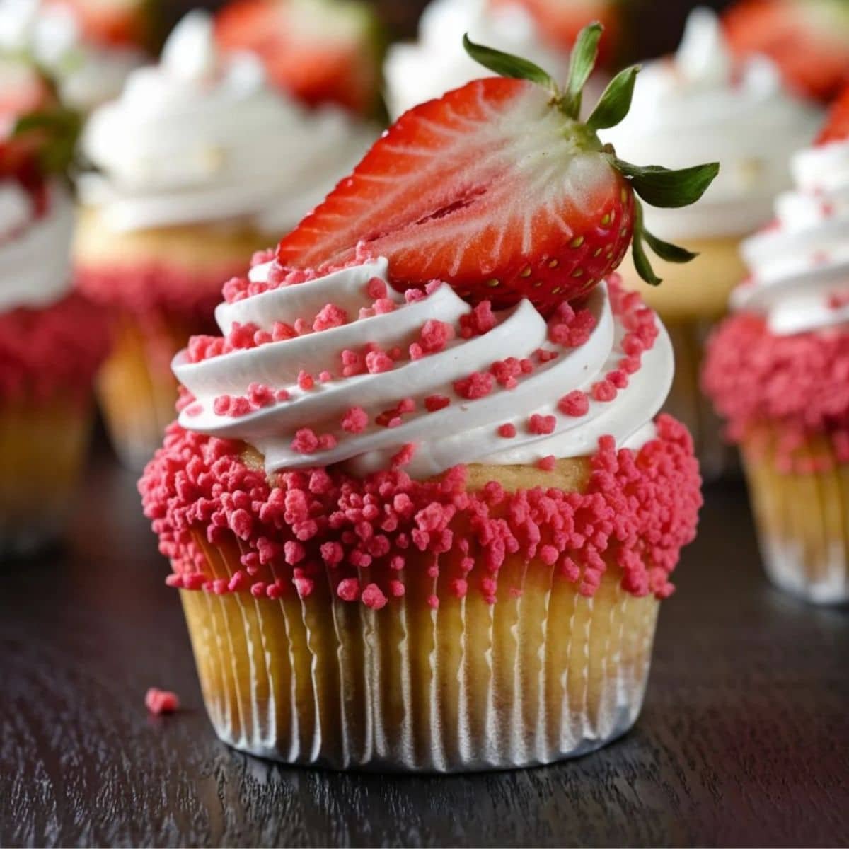 Decadent Strawberry Crunch Cupcakes topped with swirls of whipped cream, crunchy strawberry crumble, and a fresh strawberry slice, perfect for a delightful dessert.