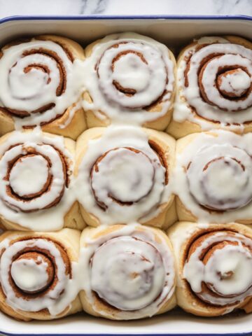 Freshly baked cinnamon rolls with creamy glaze in a white baking dish, perfect for a classic homemade cinnamon roll recipe. Soft, fluffy, and loaded with cinnamon flavor, ideal for breakfast or dessert.