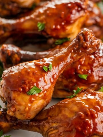 Close-up of Glazed Instant Pot Chicken Drumsticks garnished with fresh herbs, showcasing a glossy, flavorful coating.