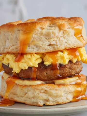 Fluffy Biscuit Breakfast Sandwich stacked with scrambled eggs, savory sausage, and drizzled with golden honey – the perfect Southern comfort breakfast.