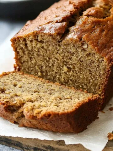 Moist banana loaf with applesauce sliced on baking paper on a counter