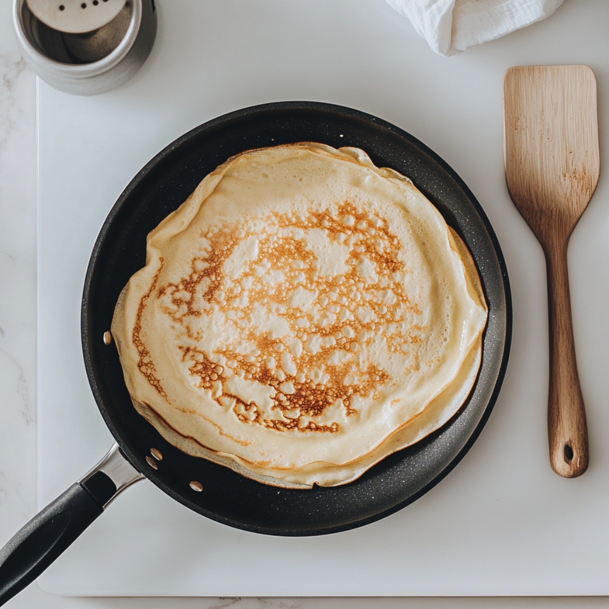 Protein crepe cooking in non-stick pan on white stove top