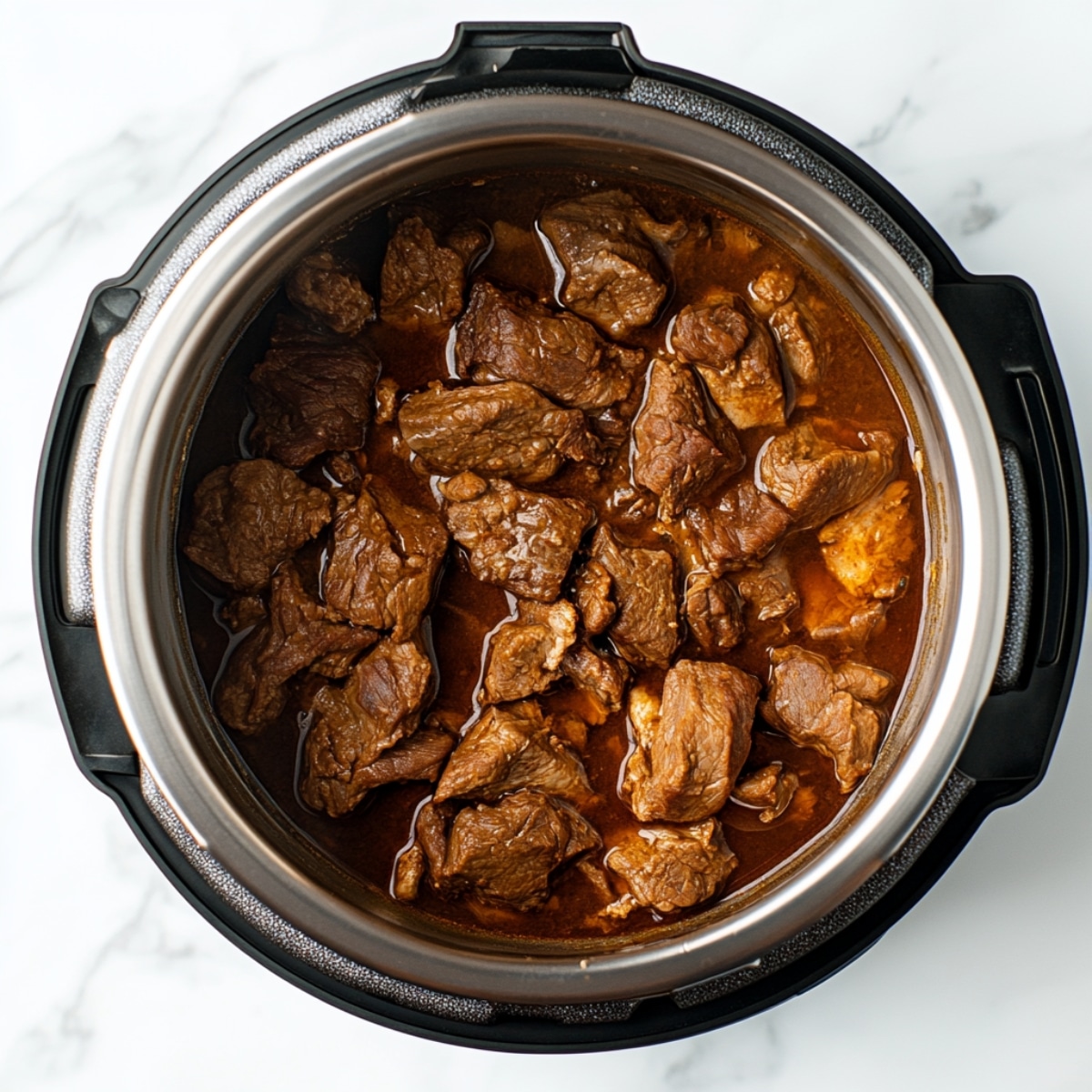 Goat meat and broth inside Instant Pot ready for pressure cooking.

