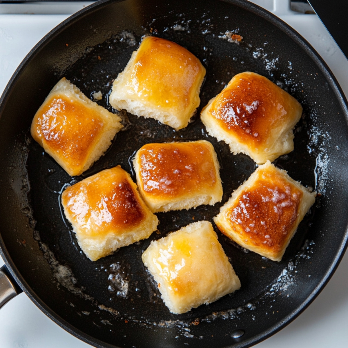 Golden brown Hawaiian Roll French Toast cooking on buttered skillet