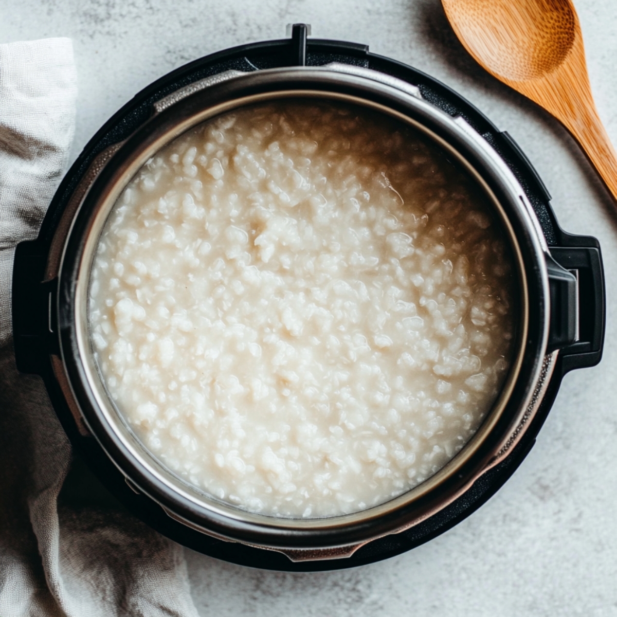 Creamy congee inside an open Instant Pot on a white kitchen counter

