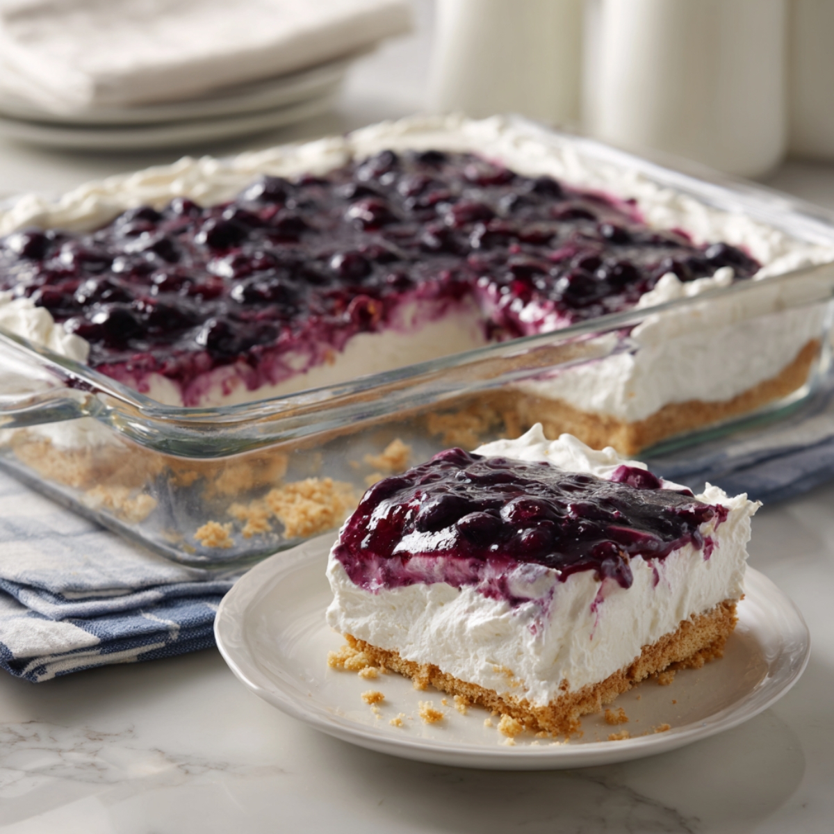 Finished Blueberry Delight dessert in glass dish with one slice served