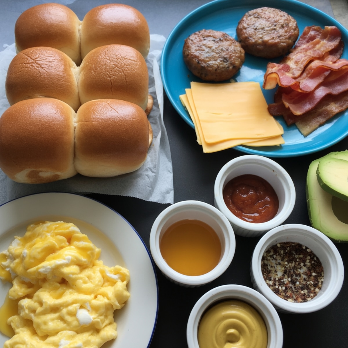 Breakfast sliders ingredients with Hawaiian rolls, eggs, bacon, and cheese