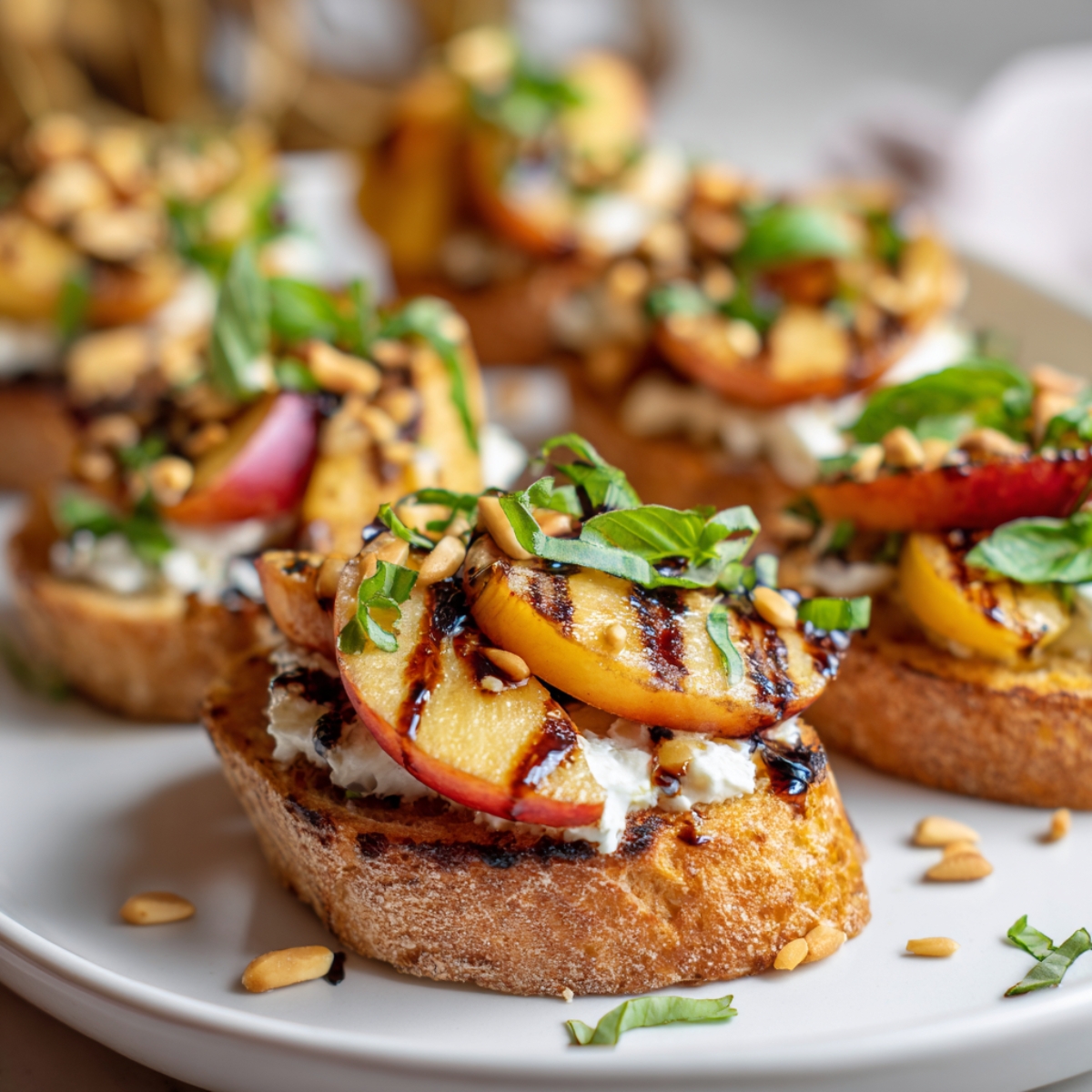 Grilled Peach Crostini assembled with cheese, grilled peaches, basil, and glaze