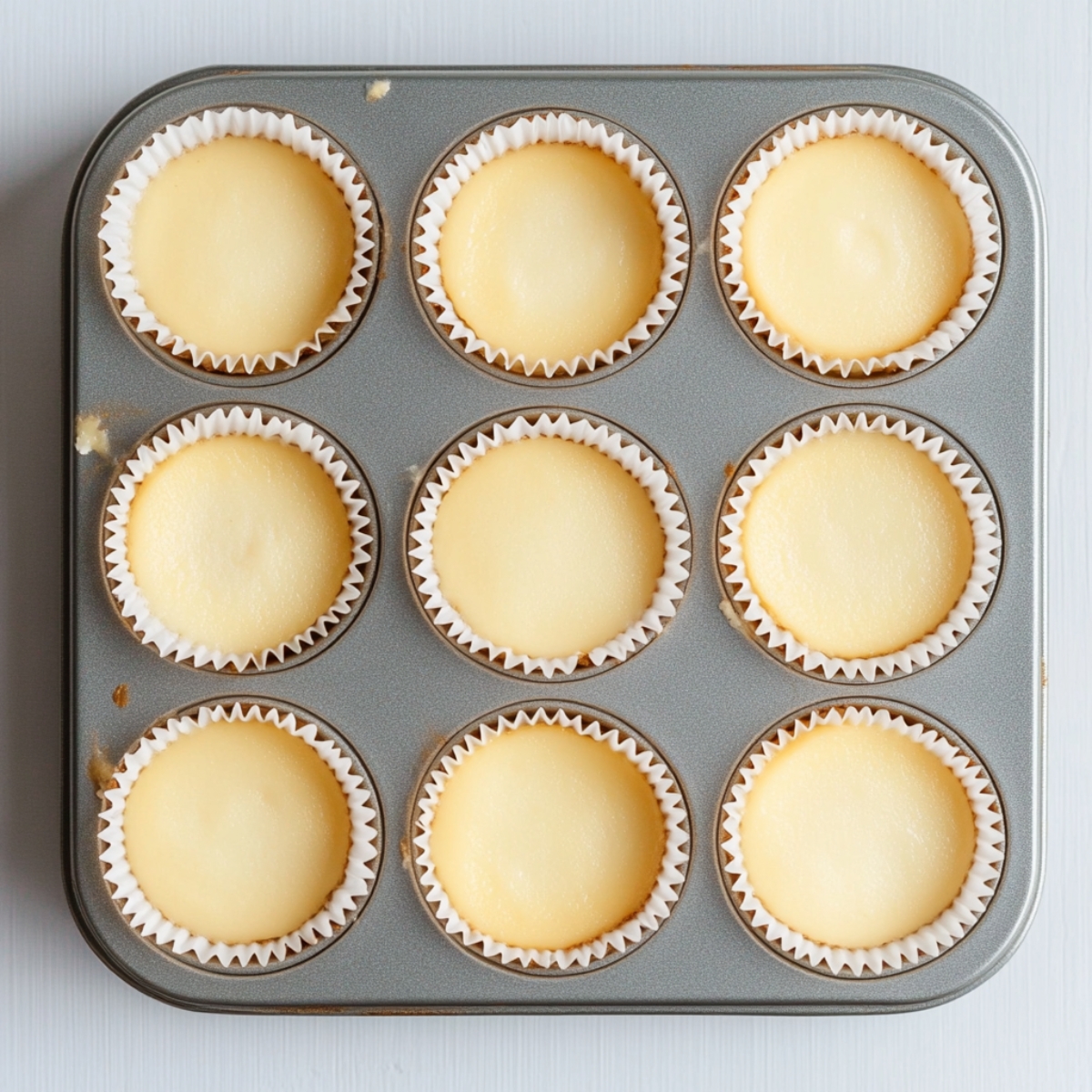 baked mini lemon cheesecakes cooling in muffin tin