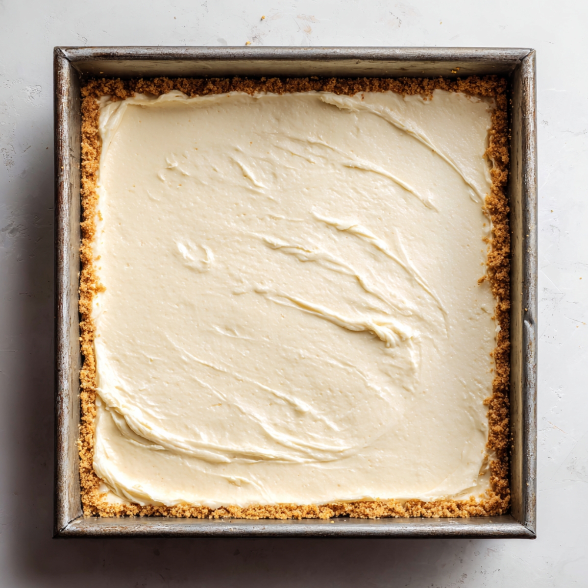 Smooth cheesecake layer spread over crust for peach cheesecake bars

