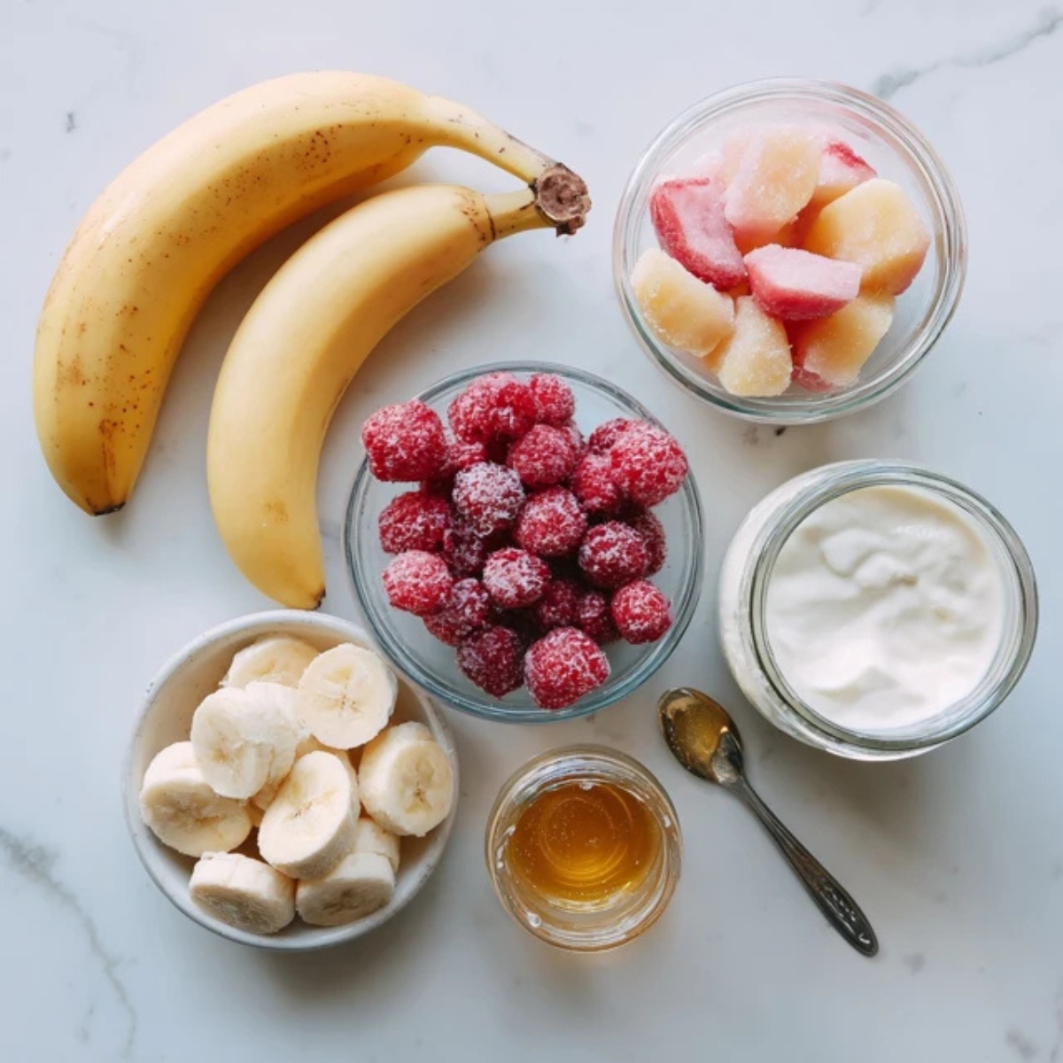 Smoothie ingredients laid out on a white counter for raspberry peach smoothie

