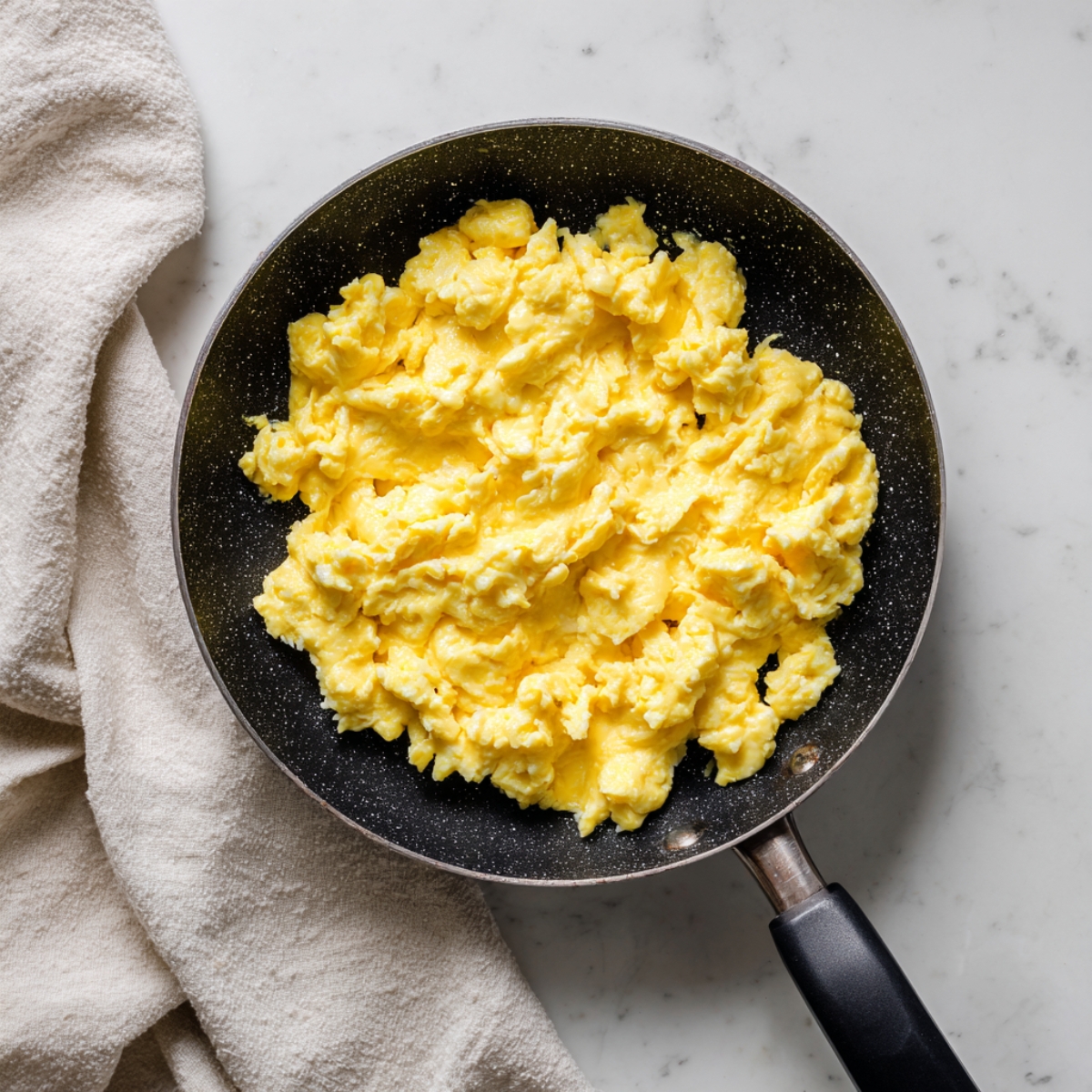 scrambled egg toast cooking with creamy eggs in skillet on white counter