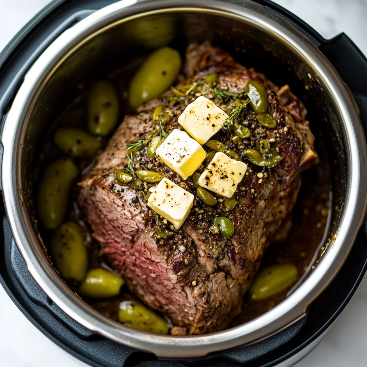Chuck roast in Instant Pot with butter, seasonings, and pepperoncini