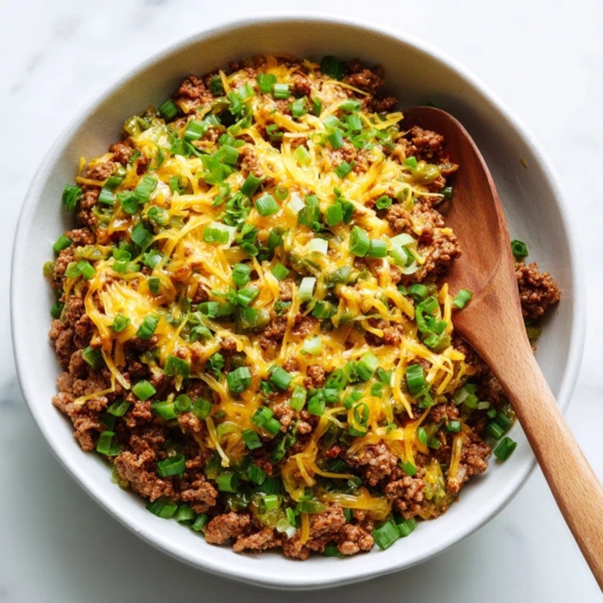 Taco ranch filling in white bowl with beef, cheese, and green onions on kitchen counter