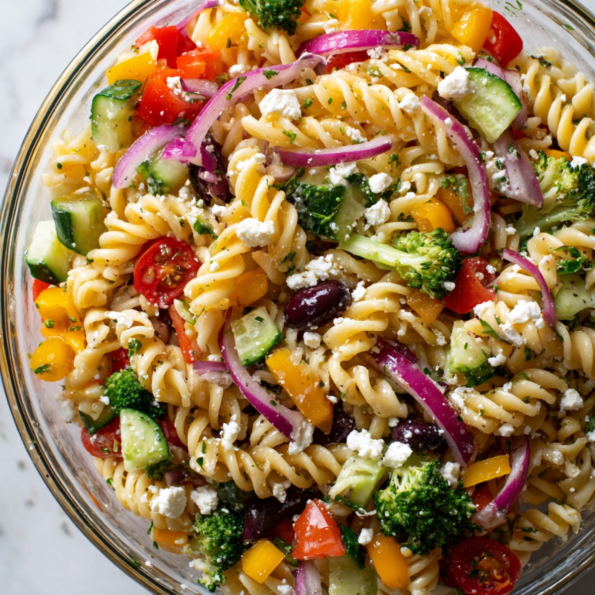 Vegetable pasta salad ingredients arranged on white counter
