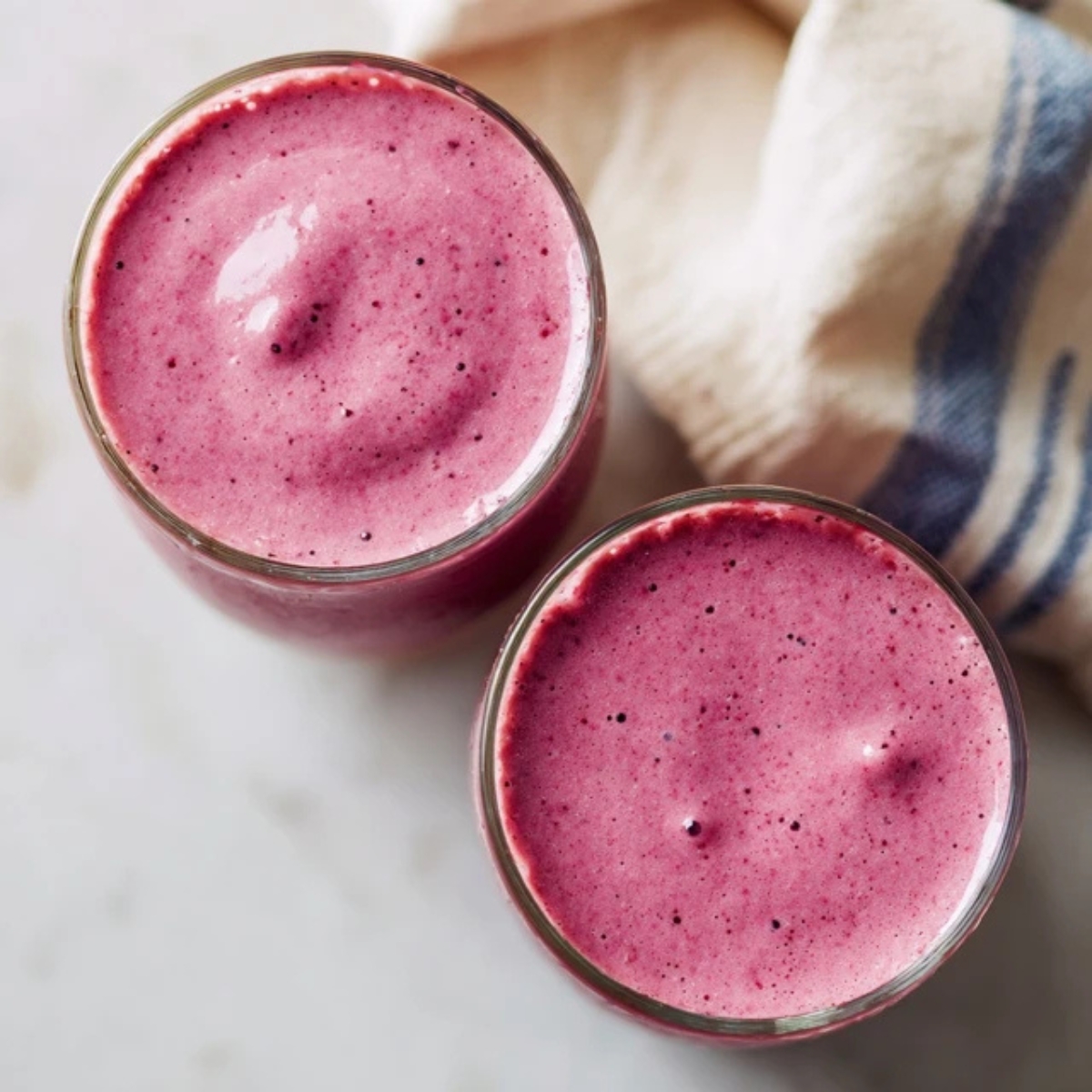 Two glasses of berry smoothie on kitchen counter ready to serve