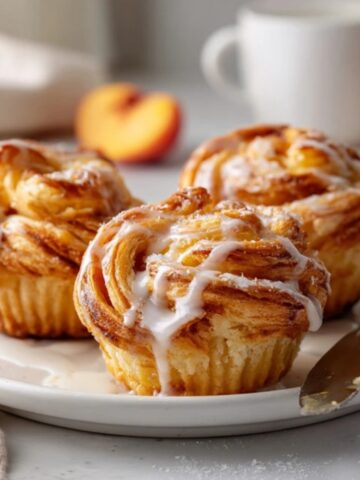 Flaky homemade peach cruffins on white plate