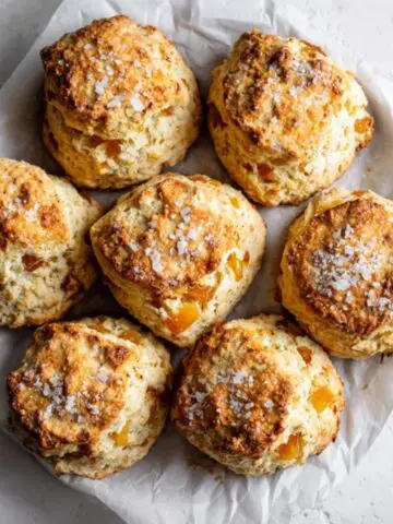 Golden flaky apricot scones with coarse sugar on white kitchen counter