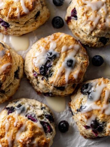Flaky glazed blueberry biscuits on white kitchen counter