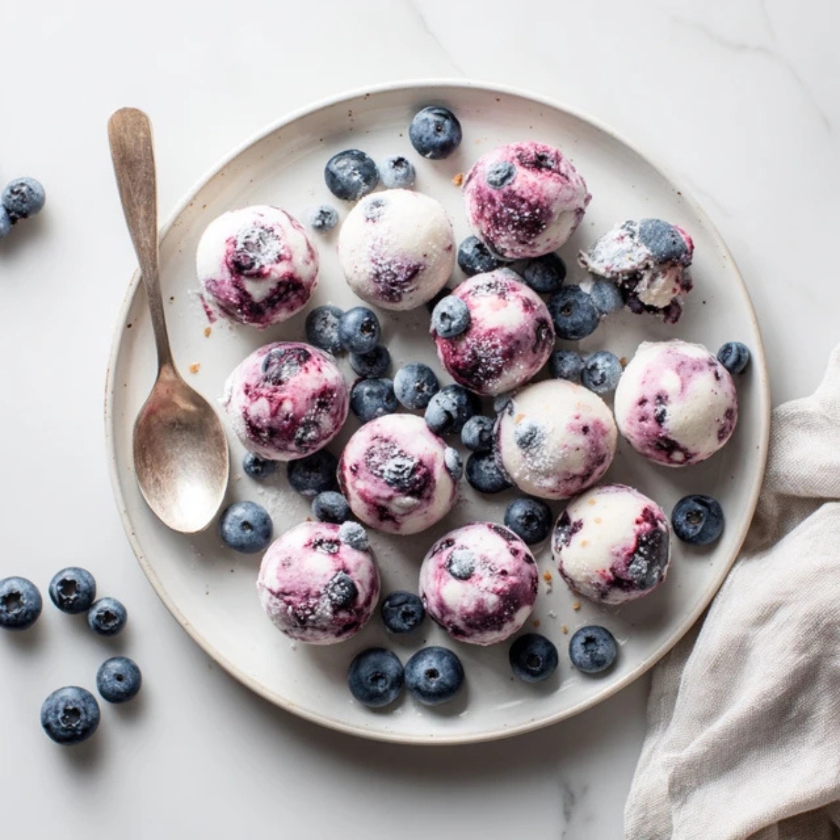 Frozen blueberry yogurt bites served on a white plate on a kitchen counter