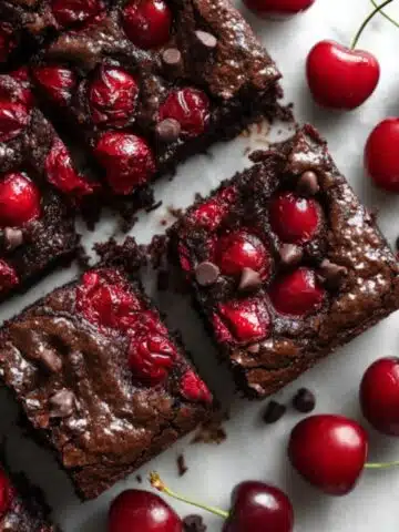 Fudgy cherry brownies cut into squares showing chocolate and fresh cherry pieces