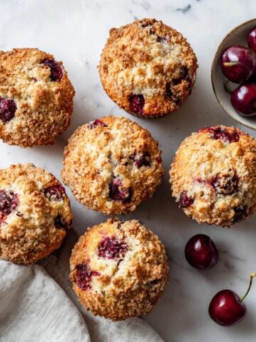 Bakery-style cherry muffins on white kitchen counter