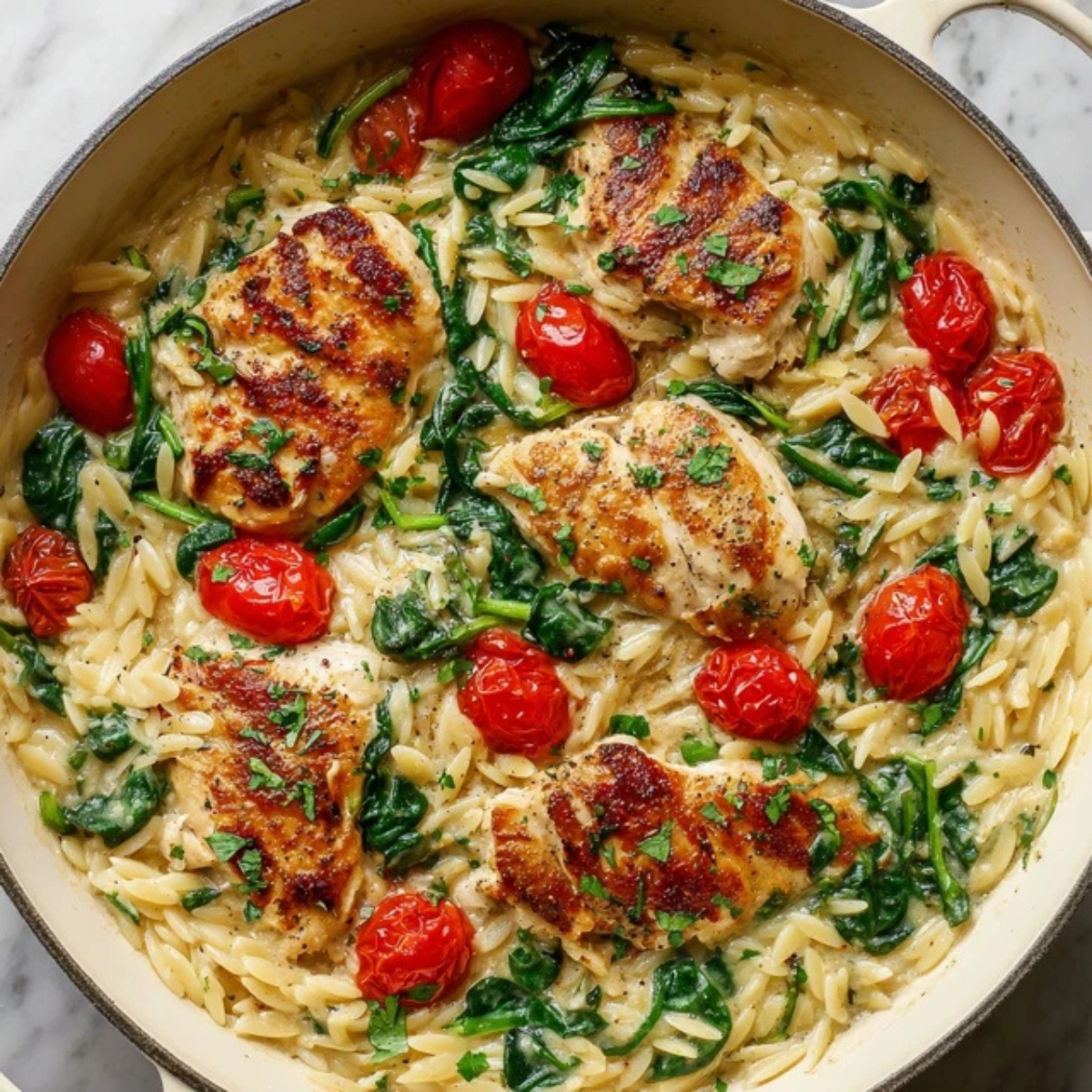 Top-down view of creamy lemon chicken orzo pasta in white skillet