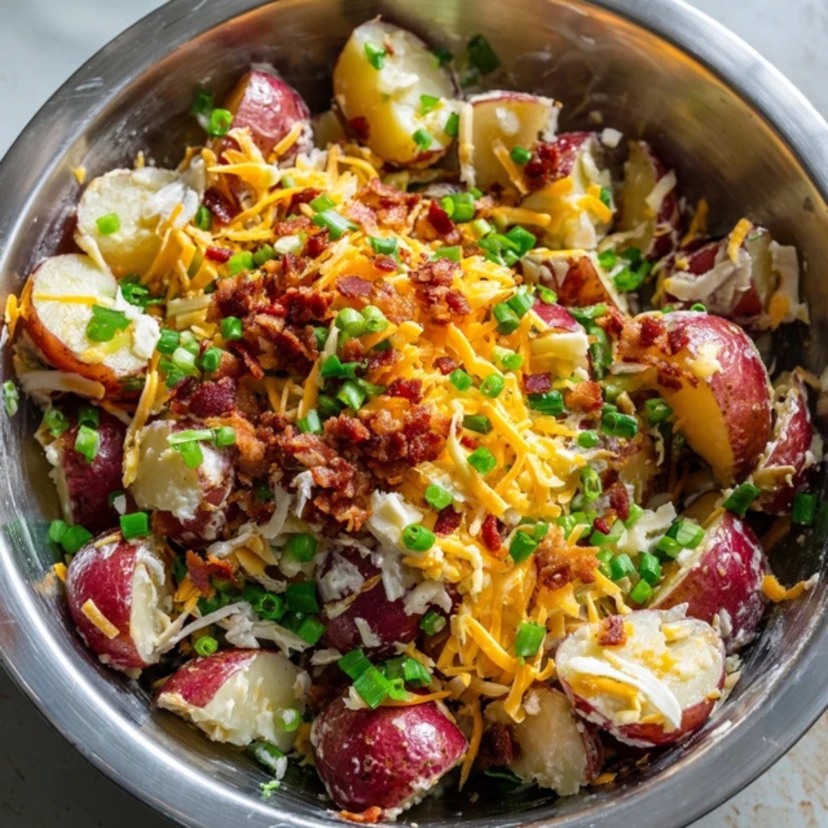 Potato salad mixed with bacon, cheese, and green onions