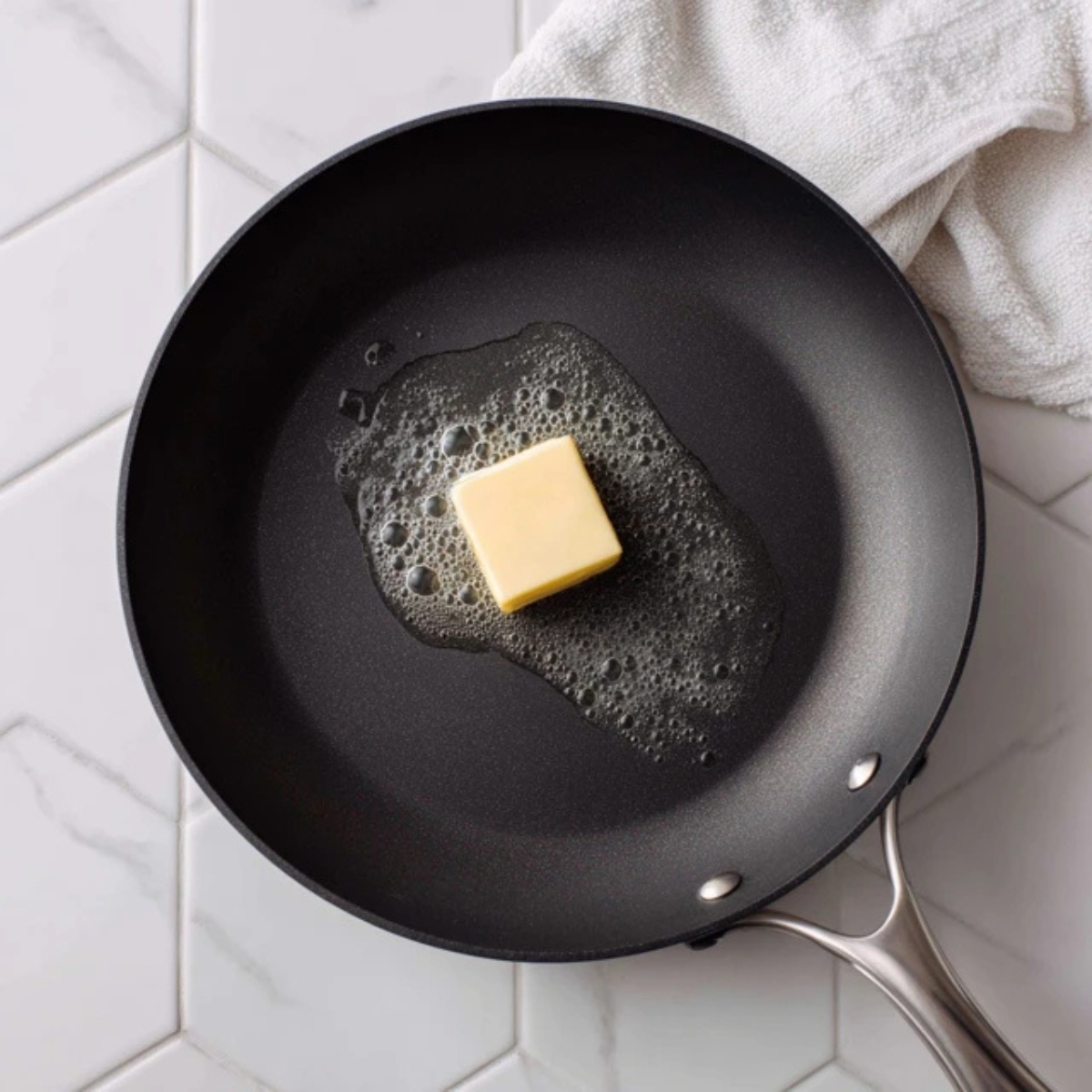 Melted butter in skillet on white counter for mini pancakes