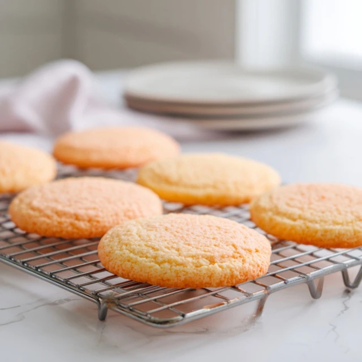 Plate of orange creamsicle cookies with glaze and orange zest on white counter