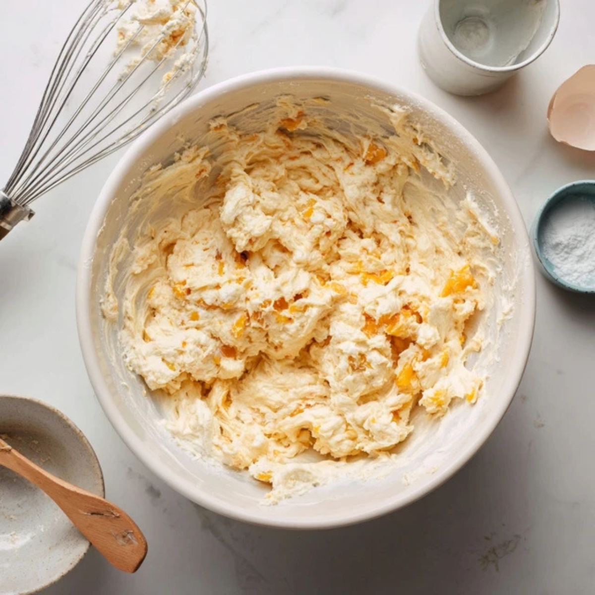 Peach fritter batter with peach chunks in a mixing bowl

