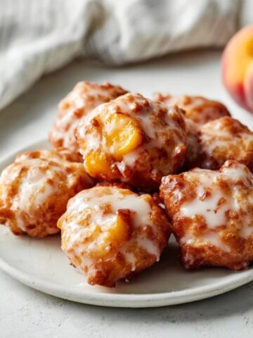 Closeup of glazed fresh peach fritters on a white plate