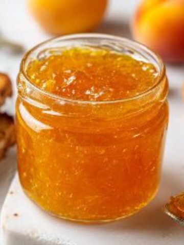 jar of homemade peach jelly on white kitchen counter