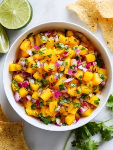 Homemade peach mango salsa with chips on white kitchen counter