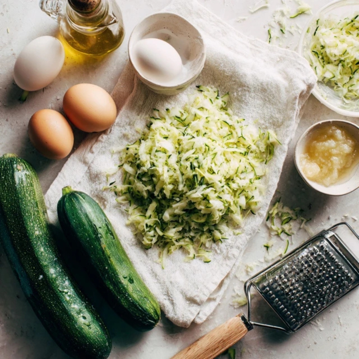 Grated zucchini and baking ingredients on white kitchen towel