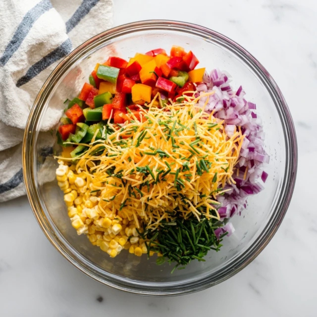 Bowl of corn, peppers, onion, cheese, and chives for frito salad