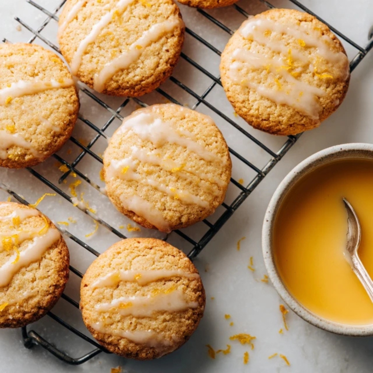 Freshly baked orange creamsicle cookies cooling on rack with glaze on side