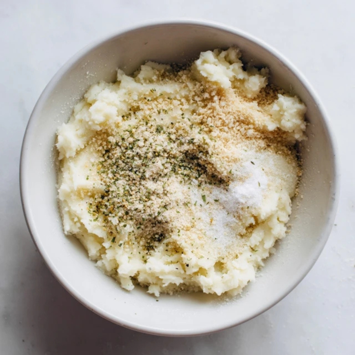 Adding panko, flour, and seasoning to mashed potato cheese puff mix