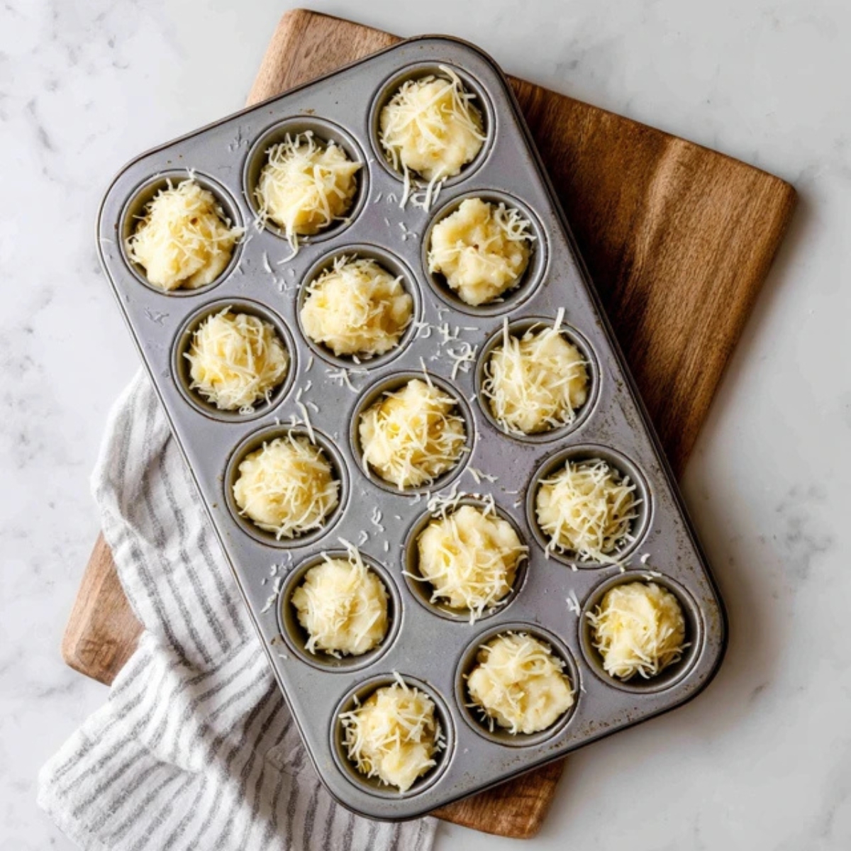 Mashed potato puffs in muffin tin topped with cheese and butter