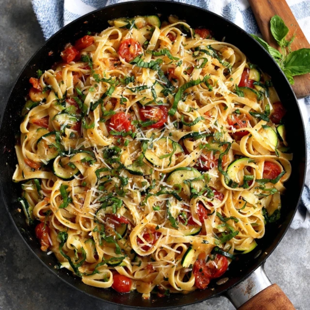 Zucchini tomato pasta with basil and Parmesan in skillet

