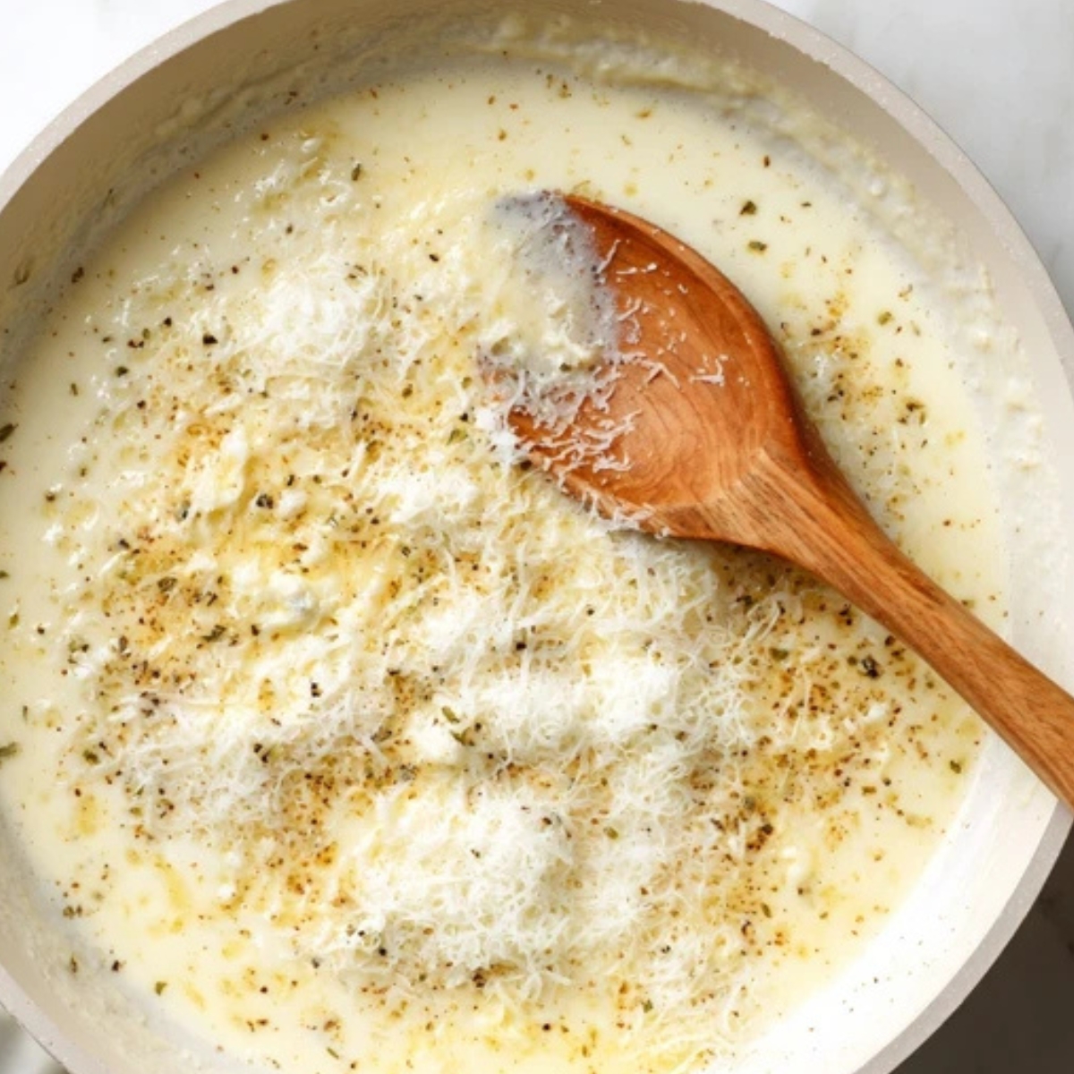 Creamy garlic sauce simmering in white skillet