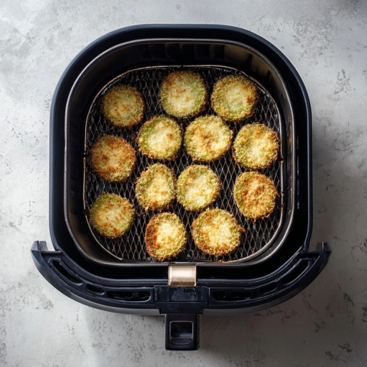 breaded tomatoes in air fryer basket before cooking