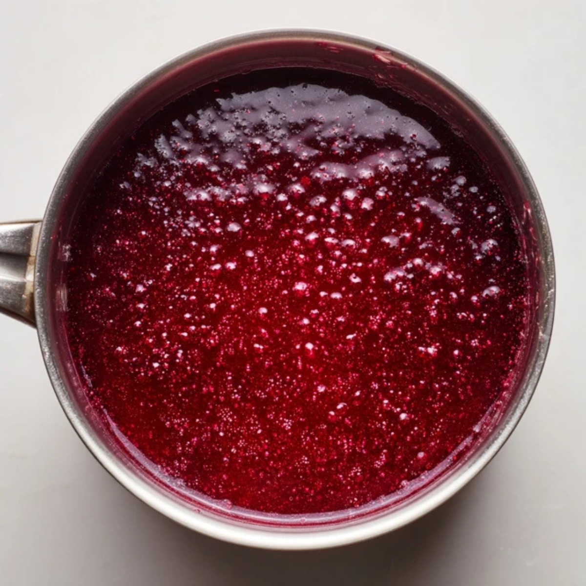 Plum juice boiling in pot with sugar to make jelly

