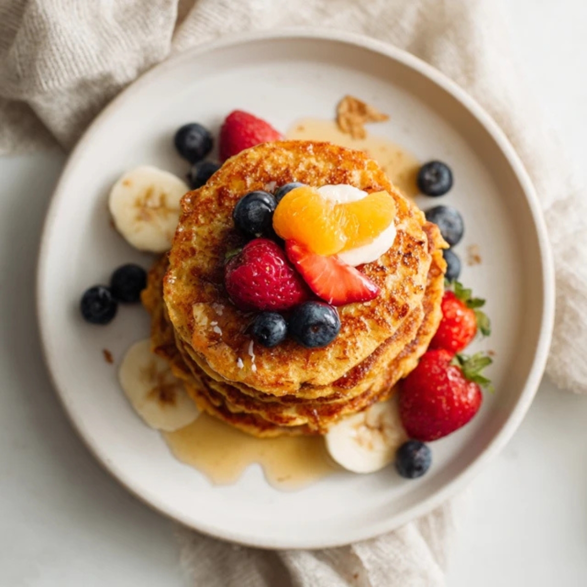 Stack of sweet potato pancakes with fruit and syrup

