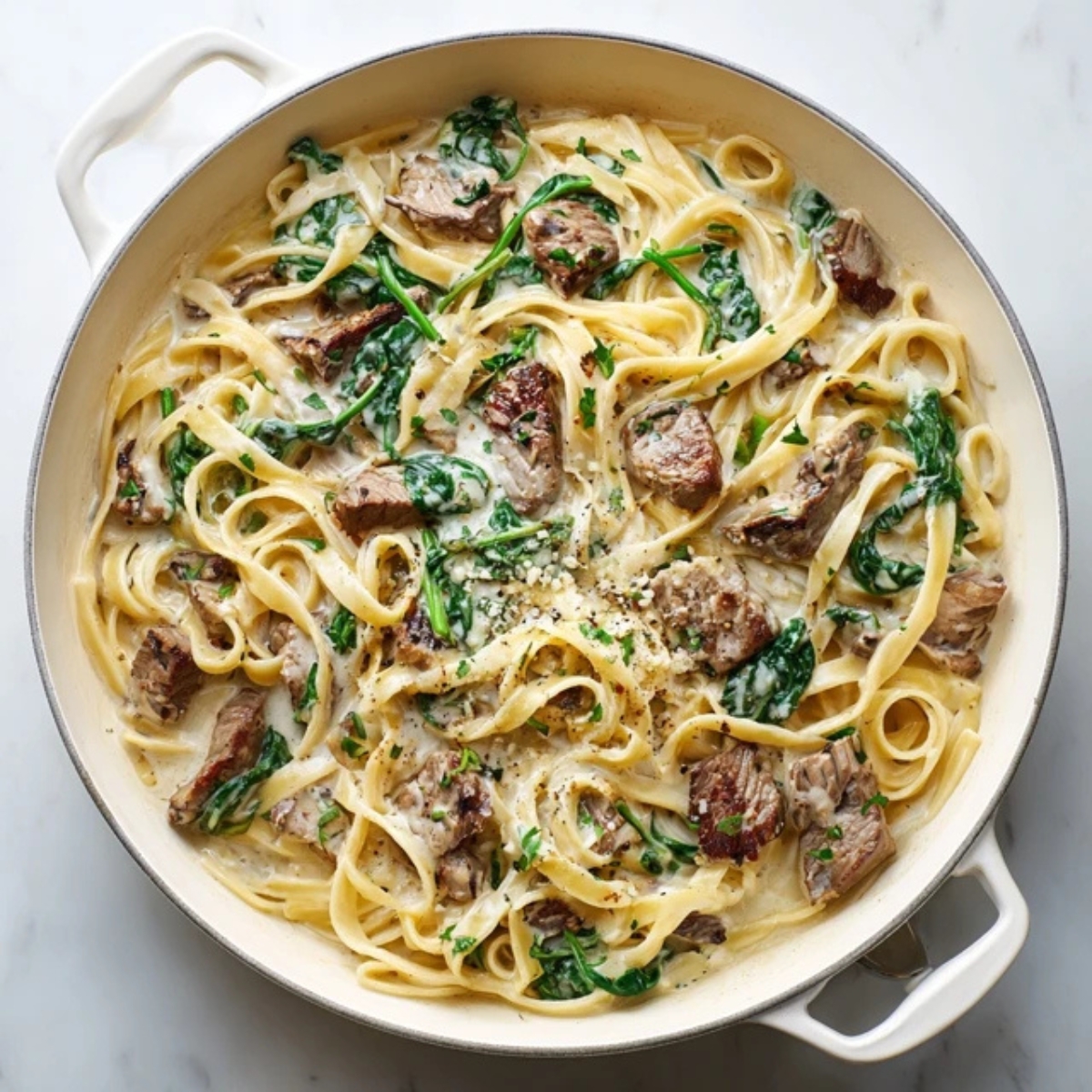 Creamy steak pasta with spinach in white skillet