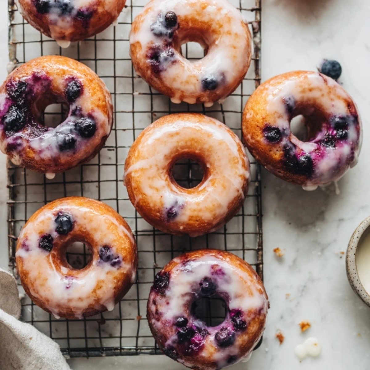 Donut pan filled with blueberry batter on white kitchen counter