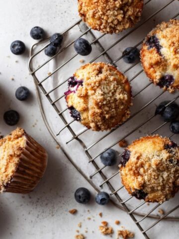 bakery-style blueberry muffins with streusel topping on white counter