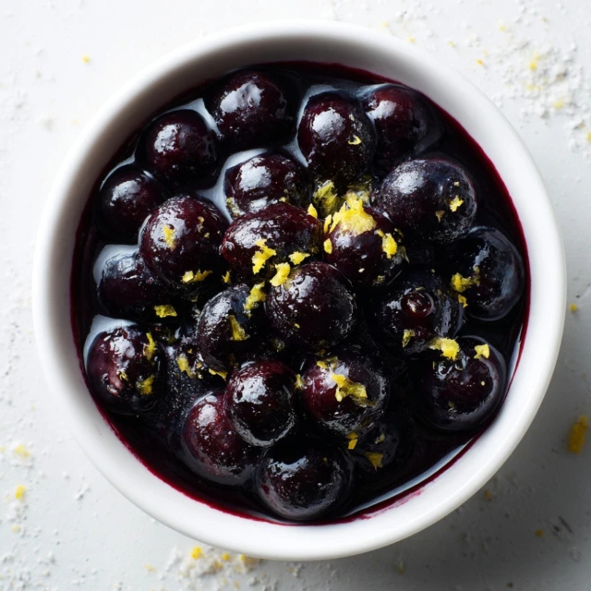 Homemade blueberry compote in white bowl on kitchen counter.